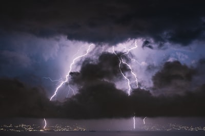 Dramatic storm clouds parting with rays of light breaking through, symbolizing transformation through difficulty