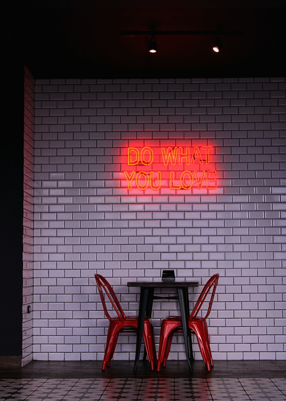 a table and two chairs in front of a brick wall