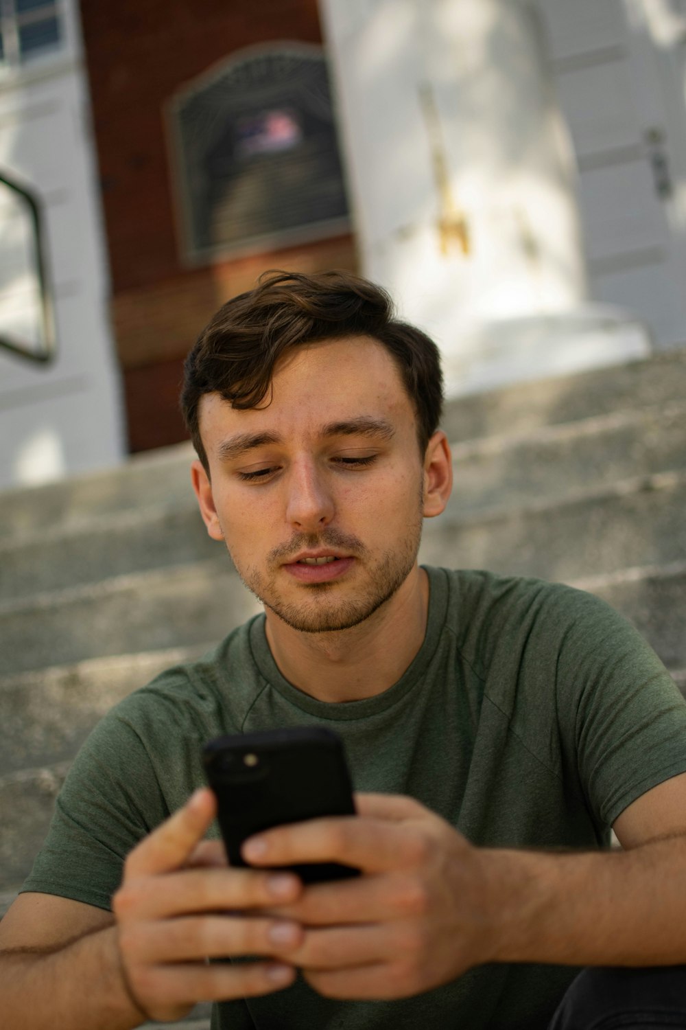 man in green crew neck t-shirt holding black smartphone