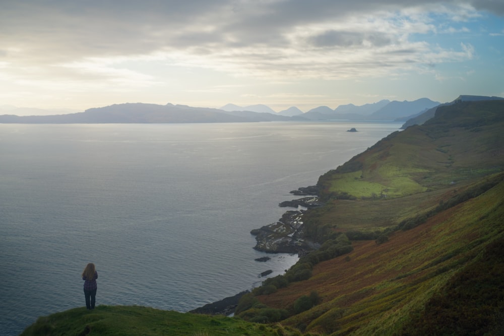 man and woman standing on green grass field near body of water during daytime