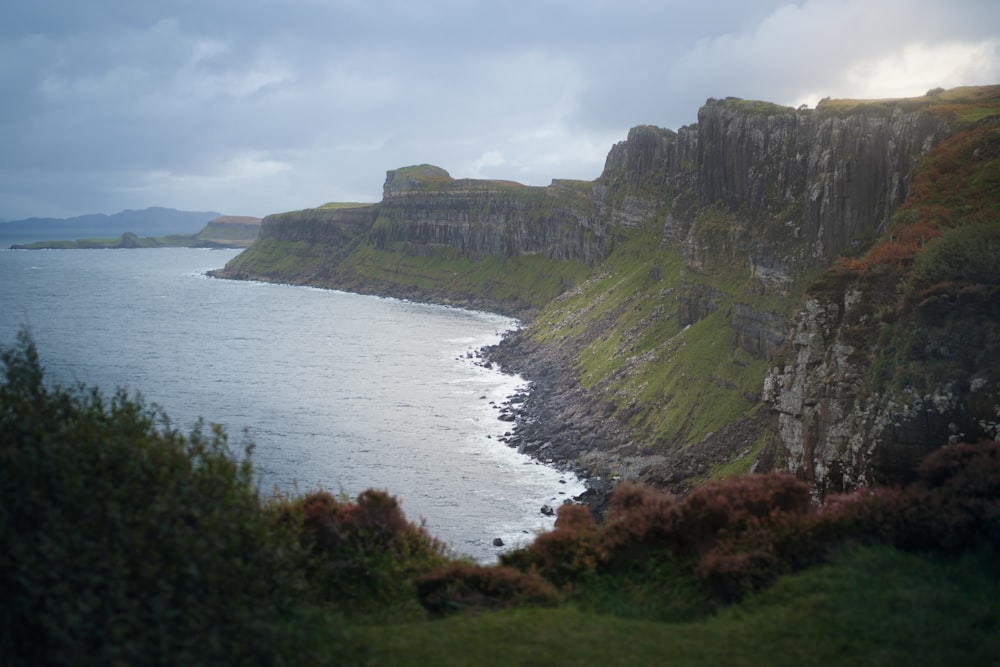 green and brown mountain beside body of water during daytime