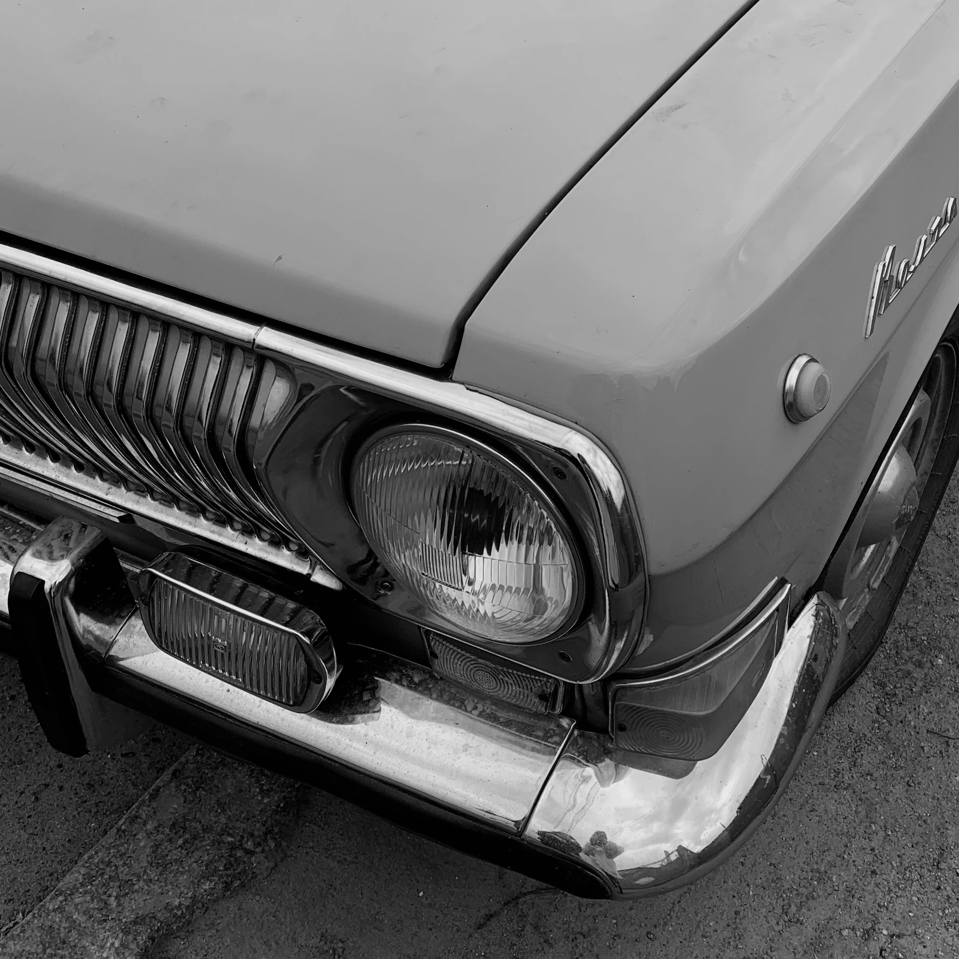 An artistic angle of a classic vintage car’s front grille and headlights, capturing the charm of aged chrome and textured paint.