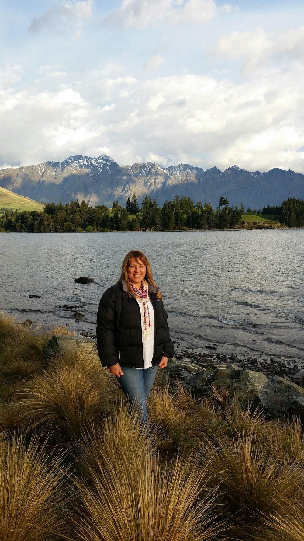 woman in black jacket standing on rocky shore during daytime