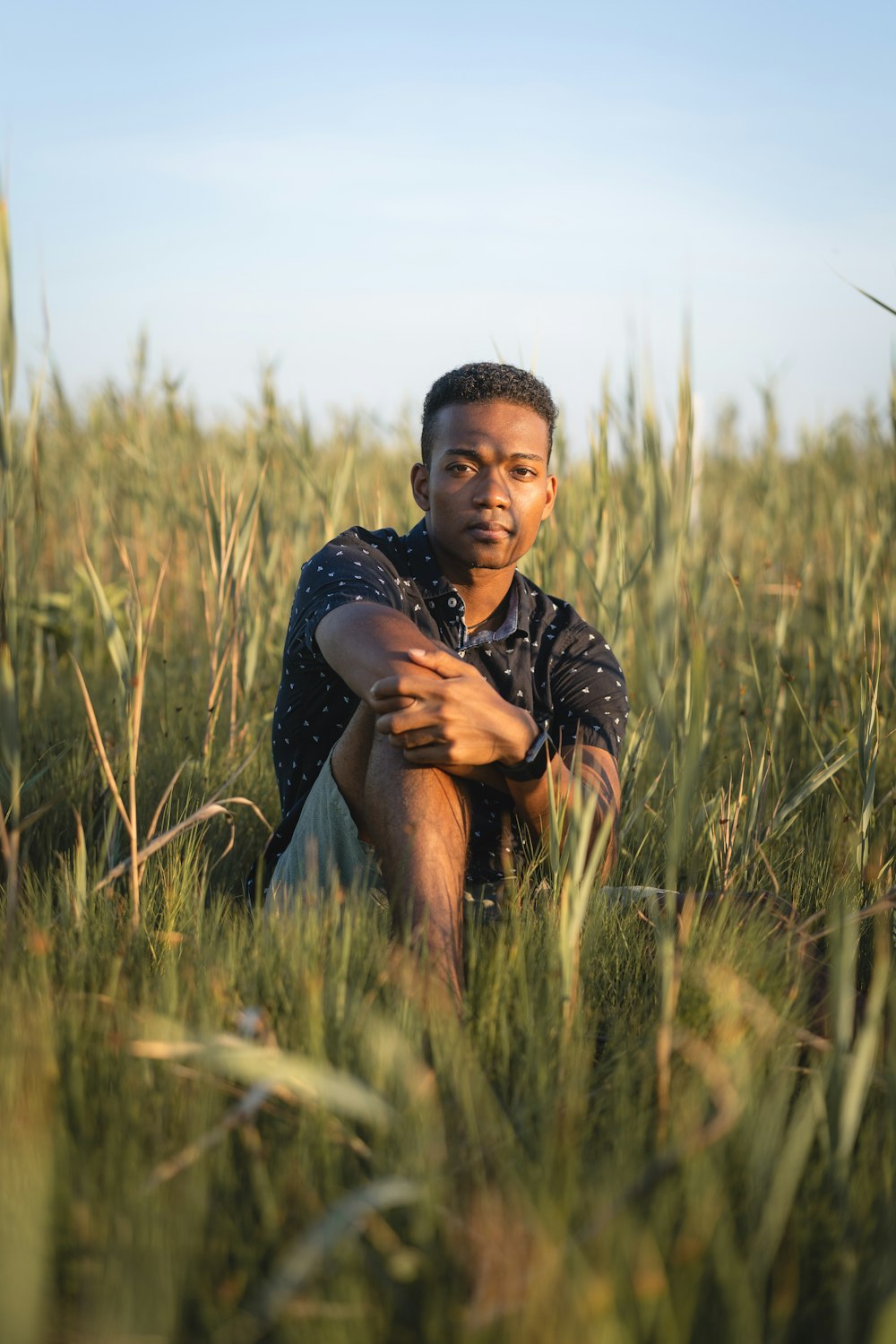 uomo in camicia nera che si siede sul campo di erba verde