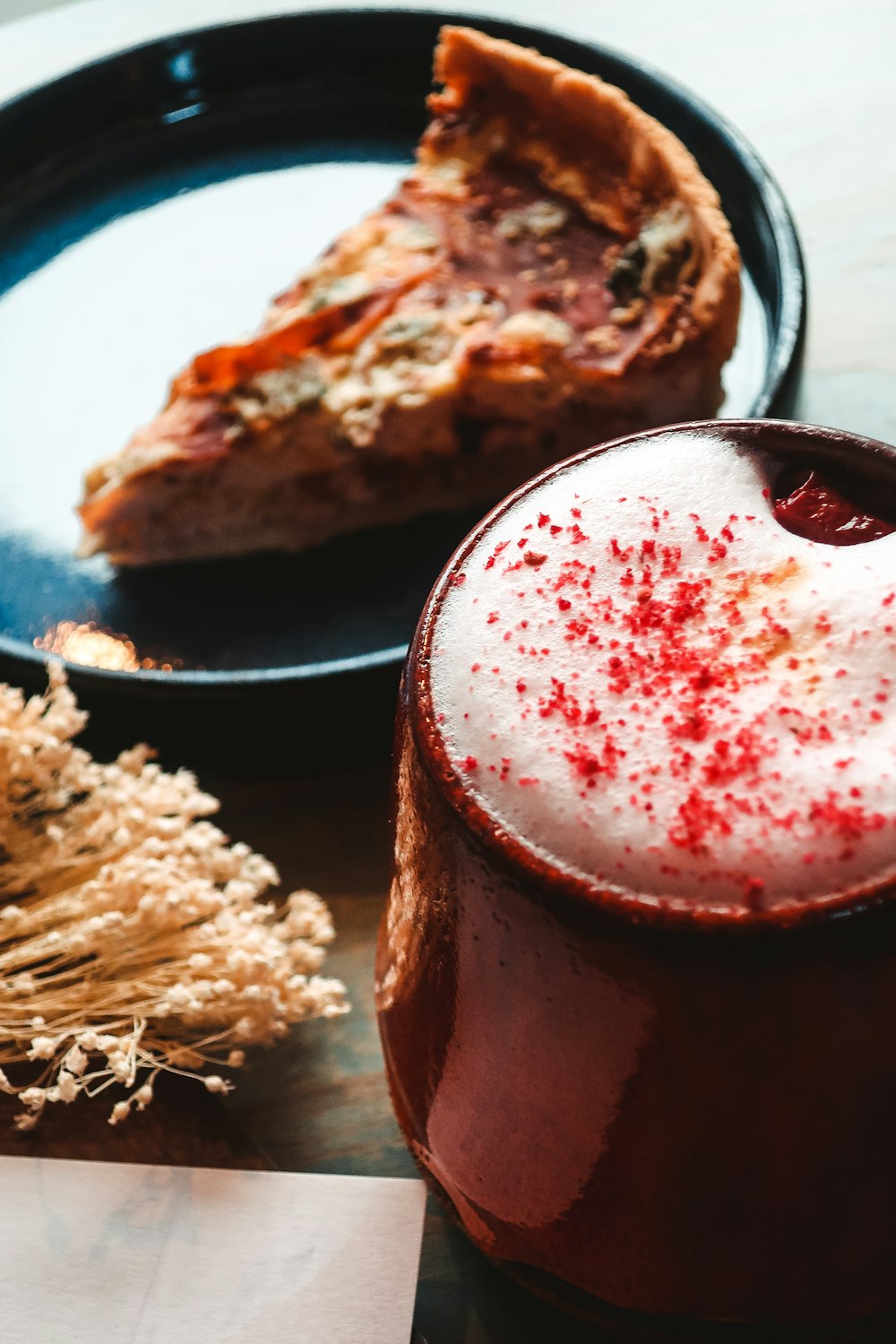 red liquid in clear drinking glass beside brown food on blue ceramic plate