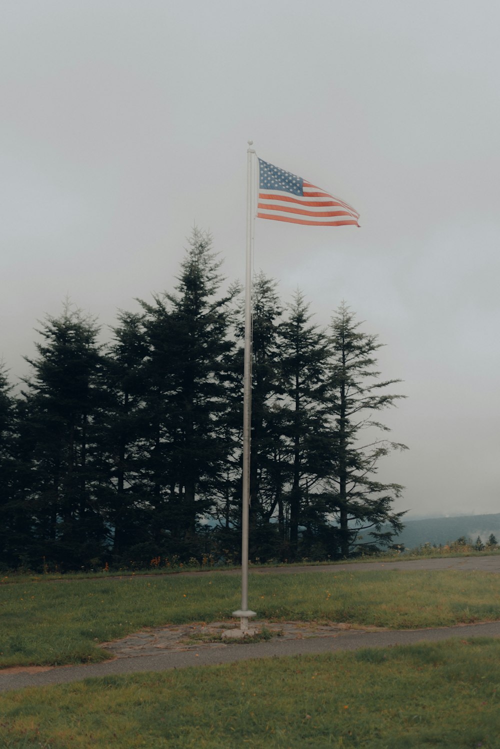 us a flag on pole near green trees during daytime