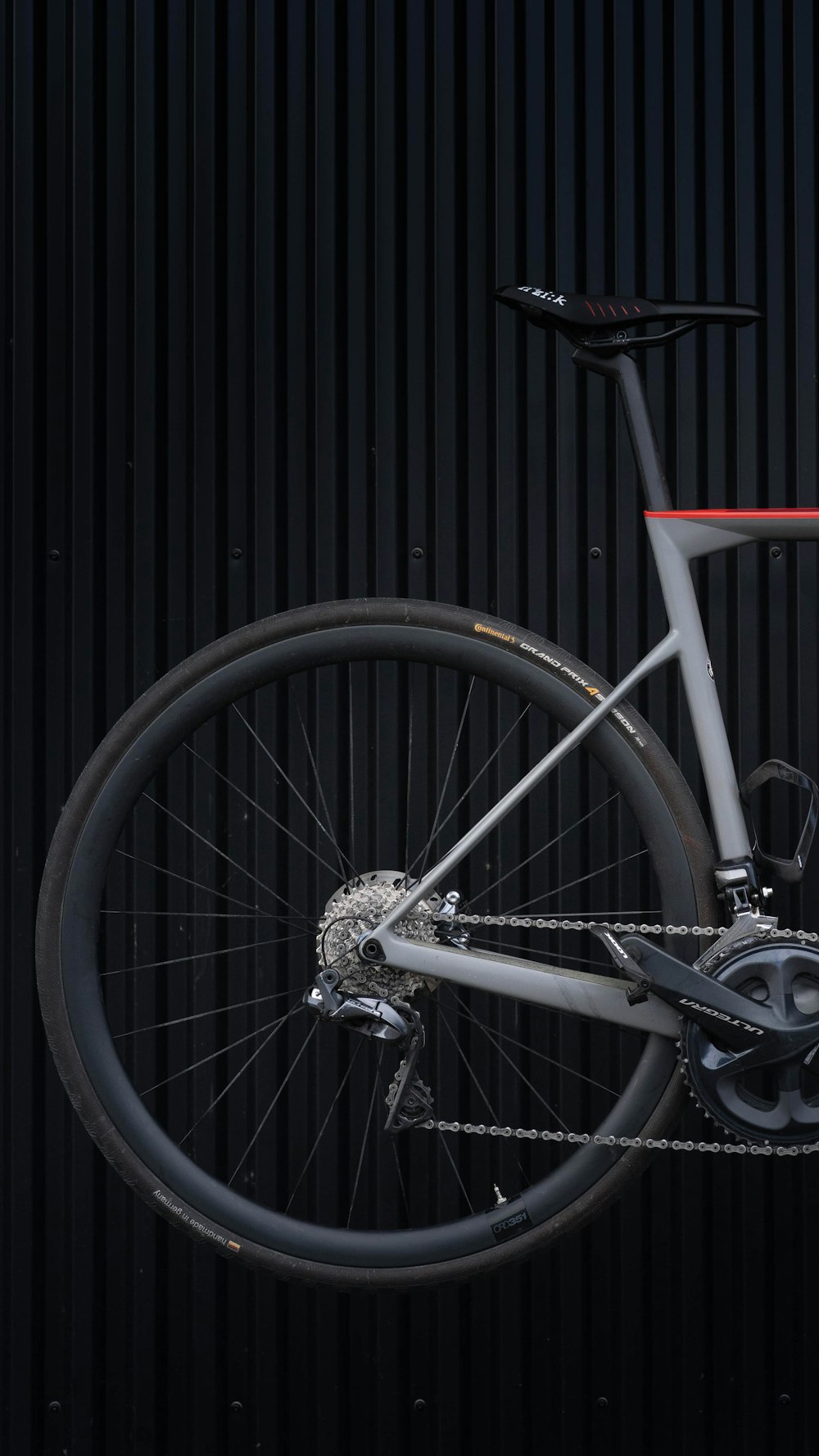 schwarz-weißes Fahrradrad an schwarze Holzwand gelehnt