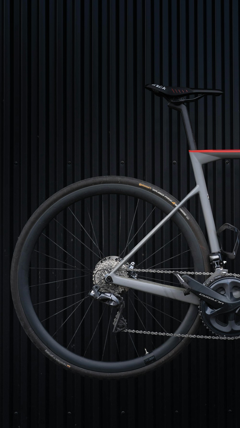 black and white bicycle wheel leaning on black wooden wall