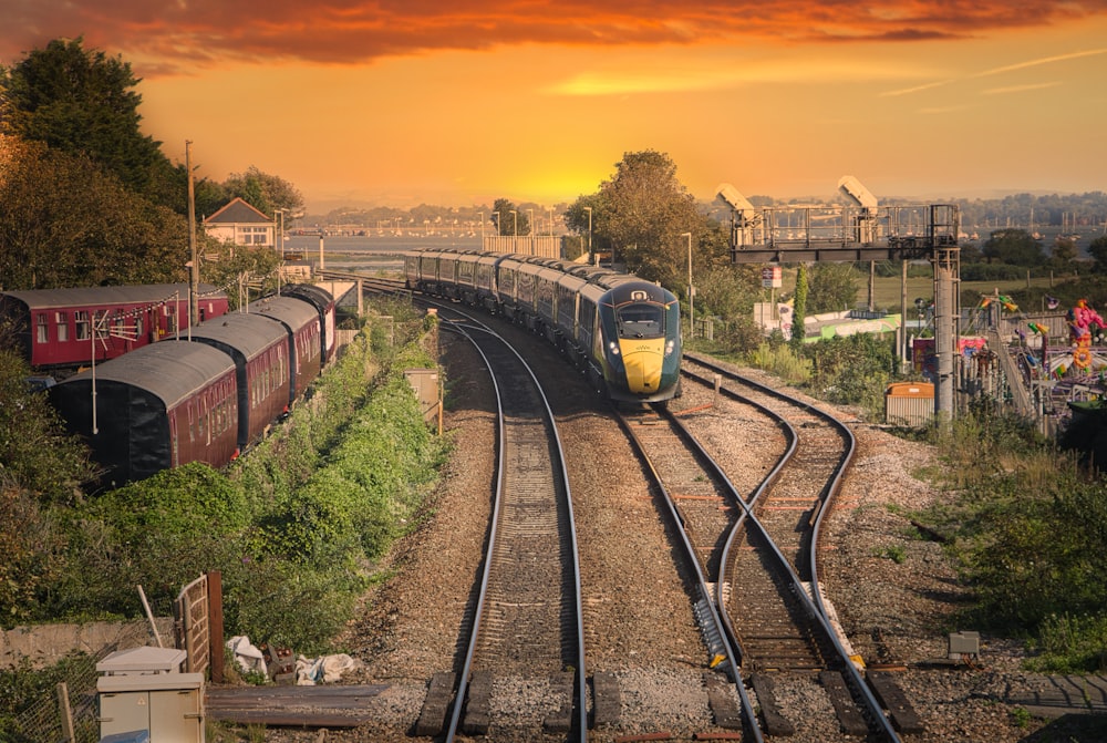 treno giallo e nero sui binari ferroviari durante il tramonto