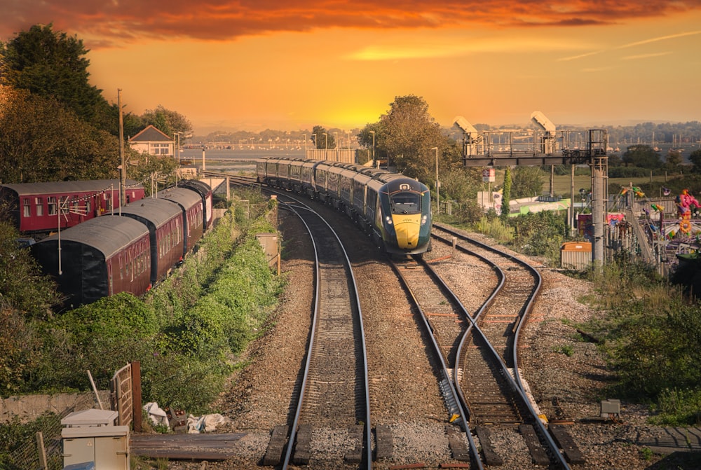 Tren amarillo y negro en las vías del tren durante la puesta del sol