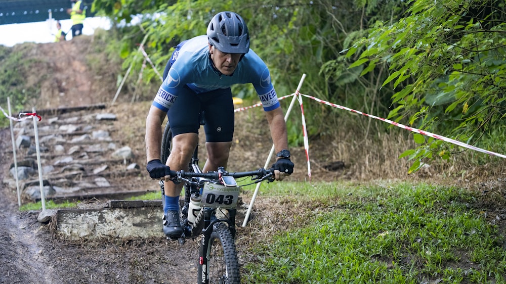 man in blue and black bicycle suit riding on black and white bicycle during daytime