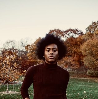 woman in red turtleneck sweater standing on green grass field during daytime