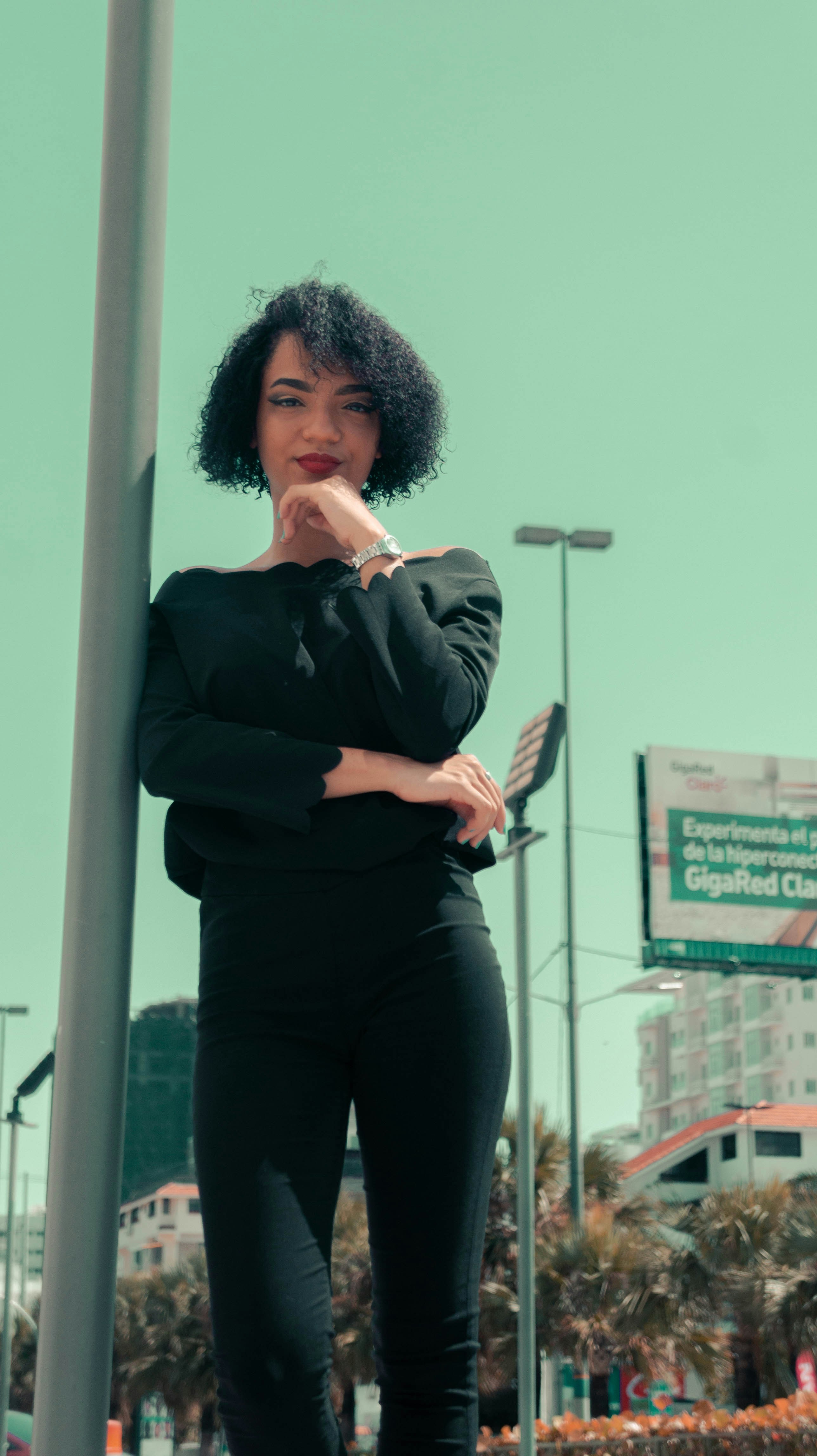 woman in black blazer and black pants sitting on white post
