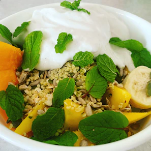 A vibrant bowl of mixed fruit chaat sprinkled with chaat masala and fresh mint leaves.
