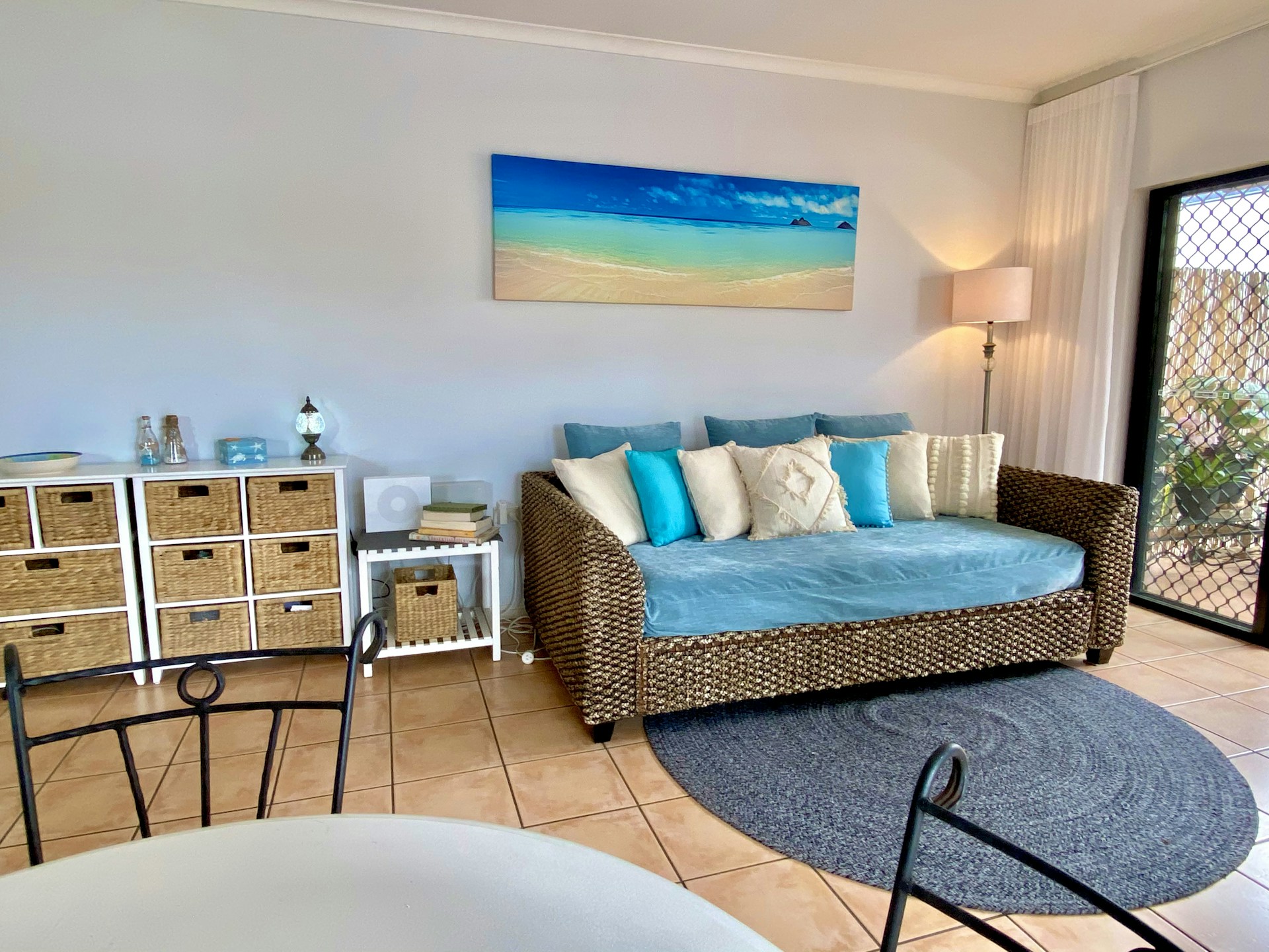 Cozy pastel-toned studio apartment with bright natural light and beach-themed decor