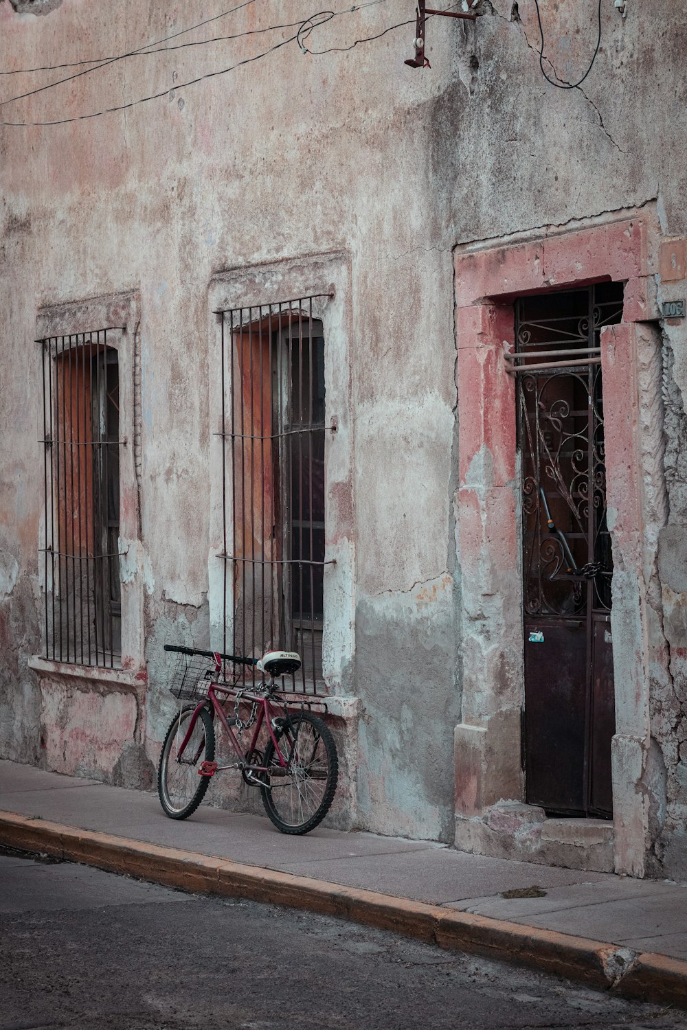 black bicycle parked beside red wooden door