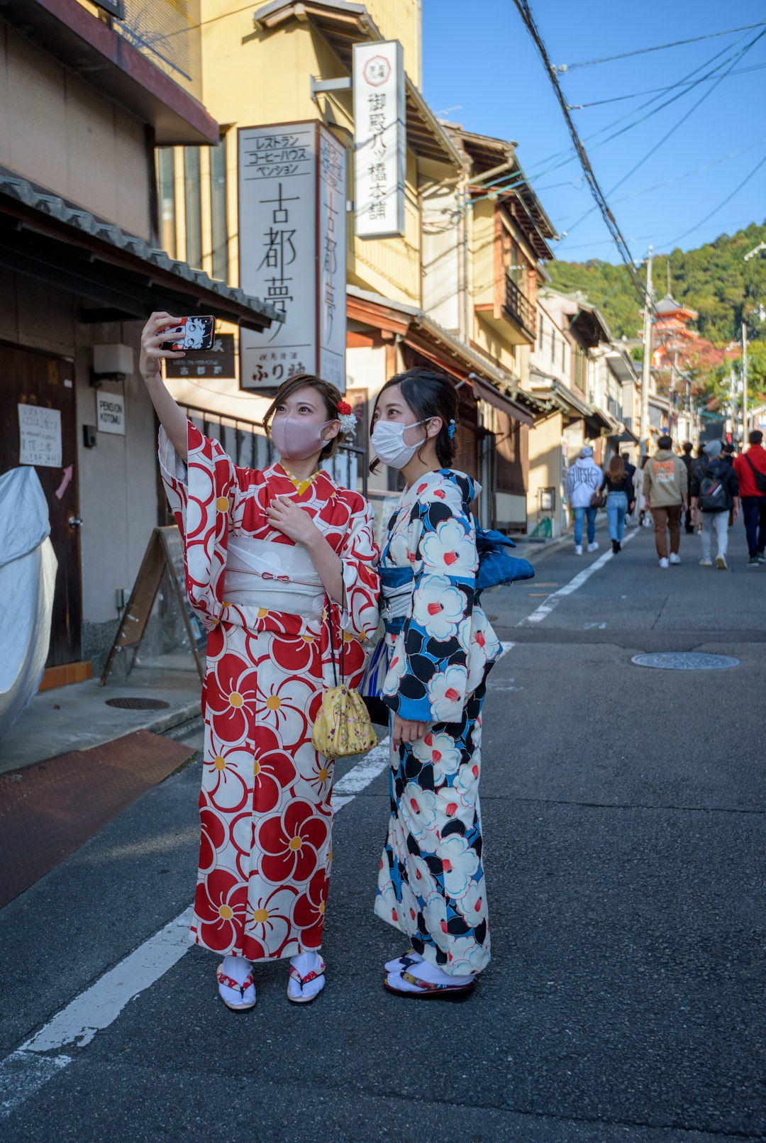 woman in white red and blue floral kimono standing on street during daytime