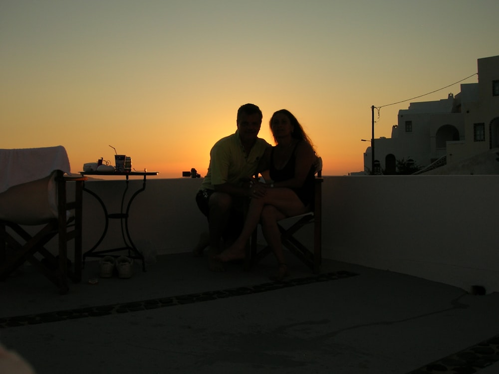 man and woman sitting on chair during sunset