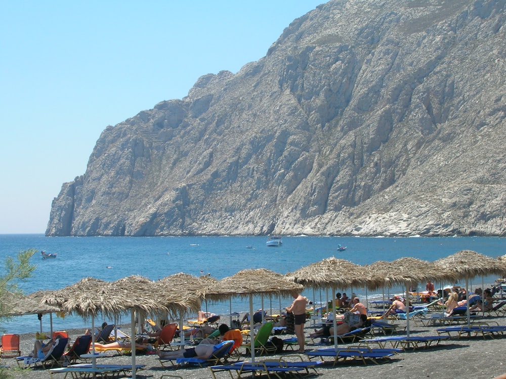 people on beach near mountain during daytime