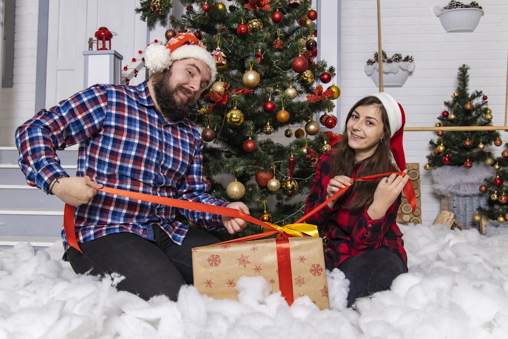 man and woman sitting on white snow