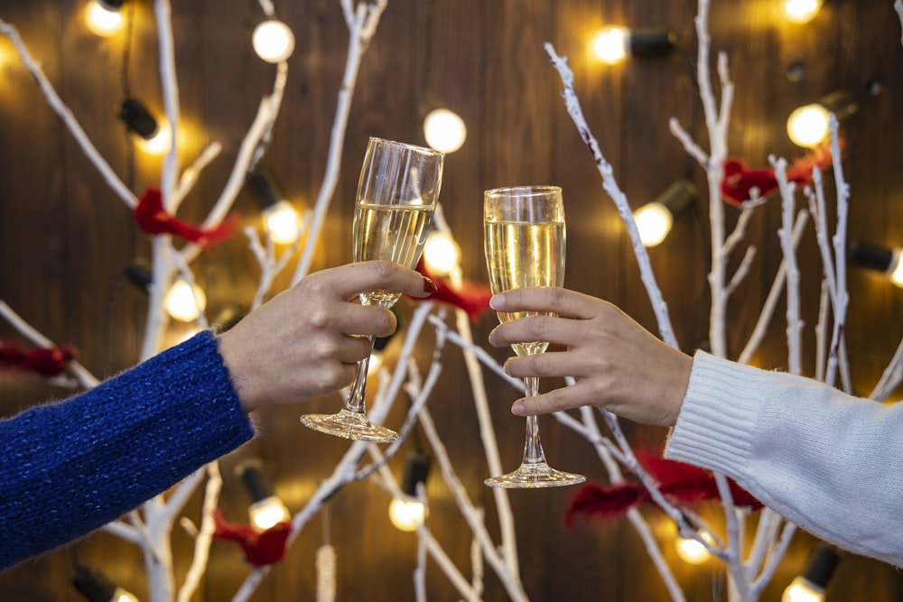 person holding wine glasses with red liquid