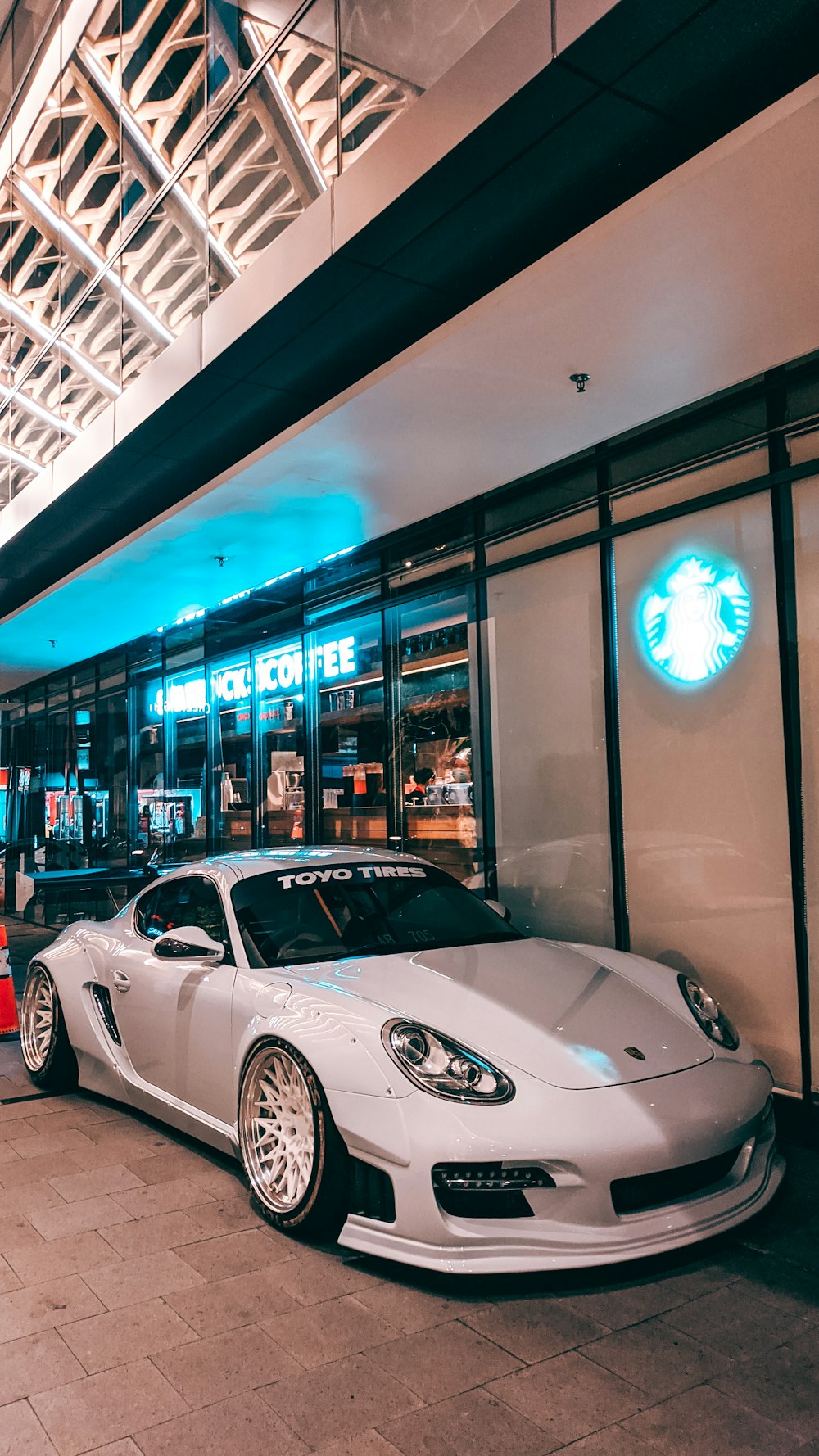 white porsche 911 parked in front of store