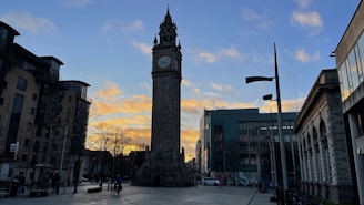 Post clock standing proudly in a bustling town square at sunset.