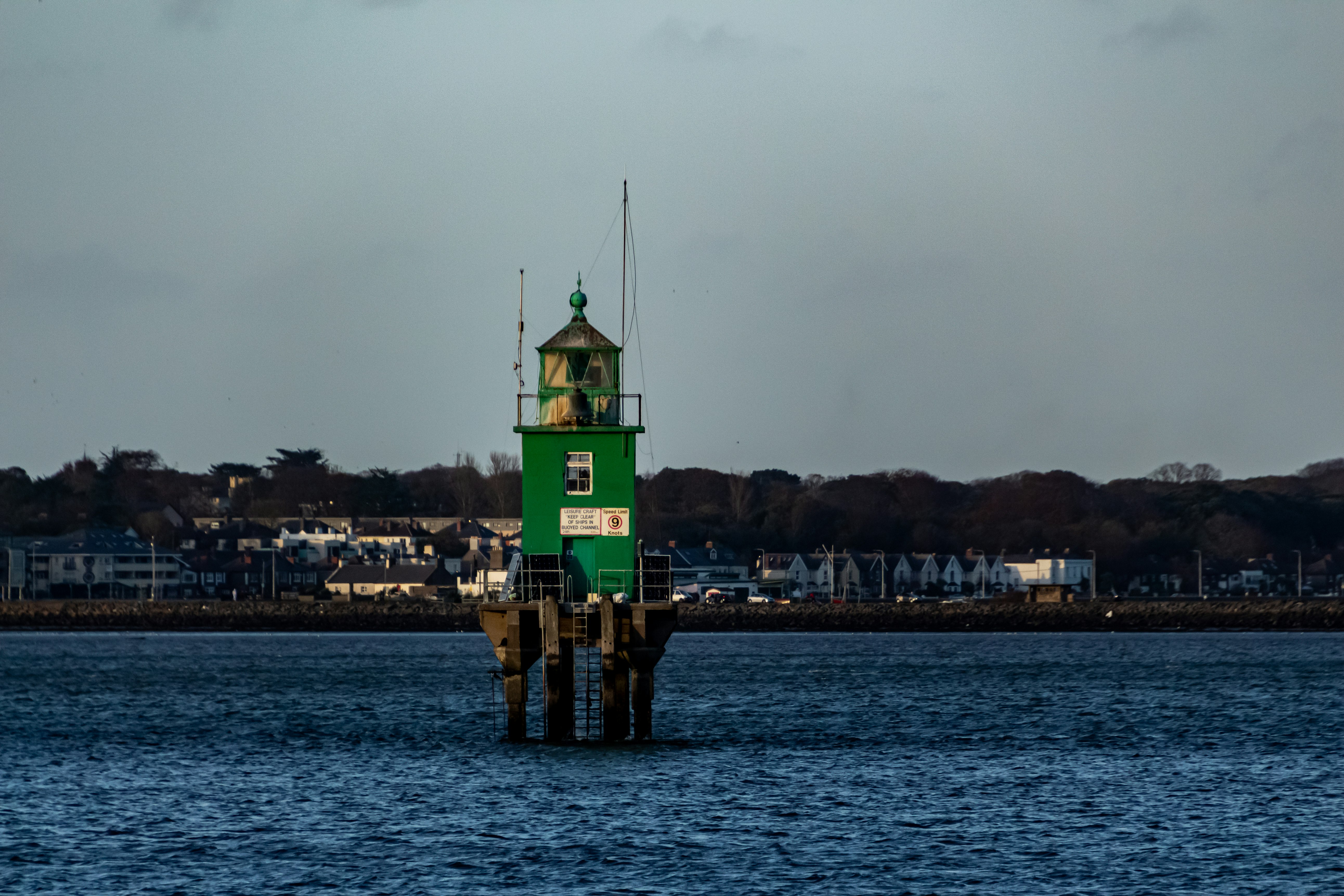 green and brown tower near body of water during daytime