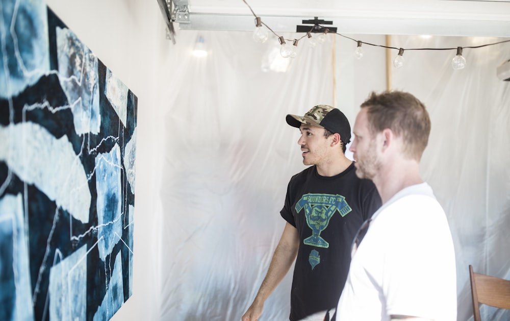 man in black and green crew neck t-shirt standing beside man in white t-shirt