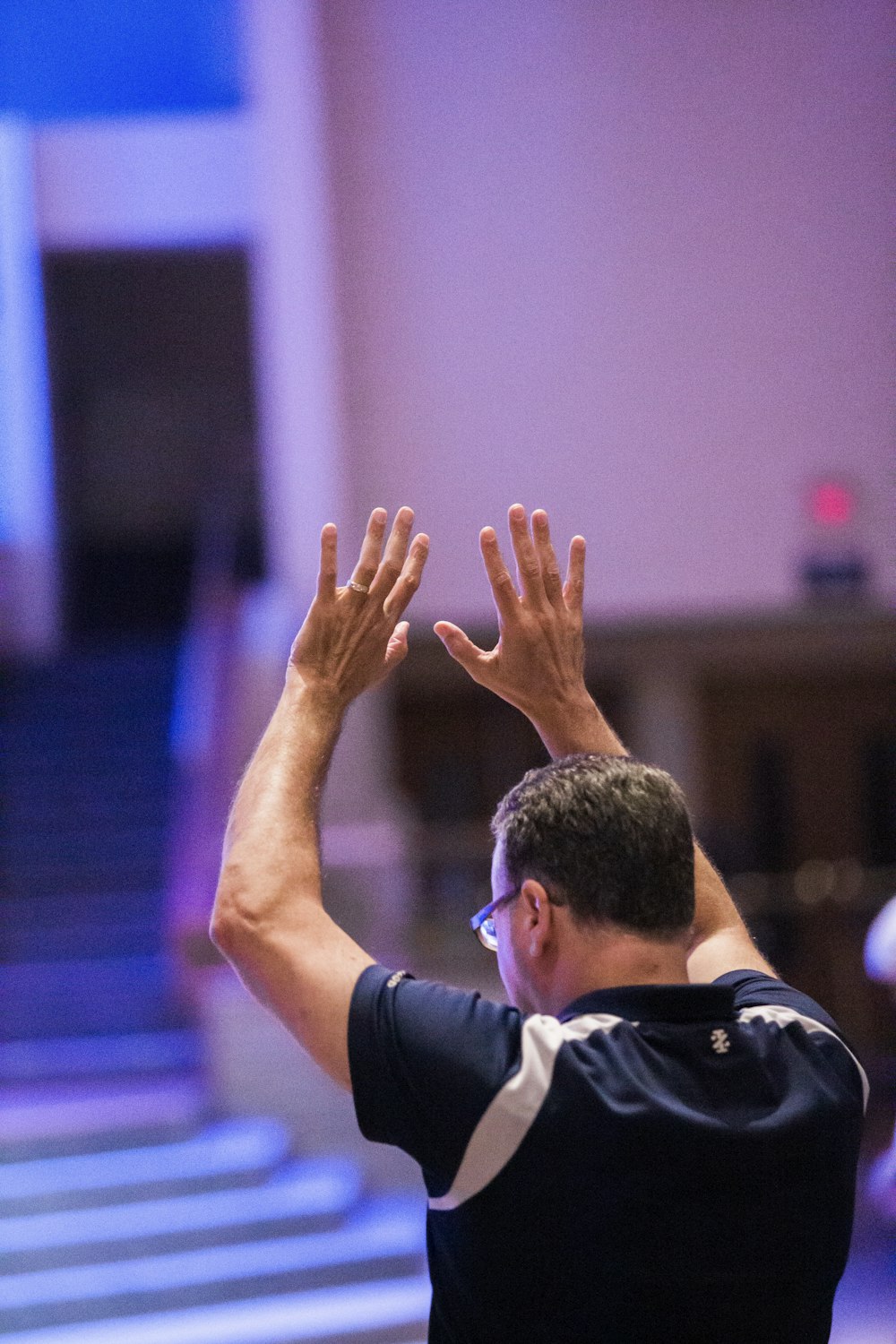 man in black and white shirt raising his hands