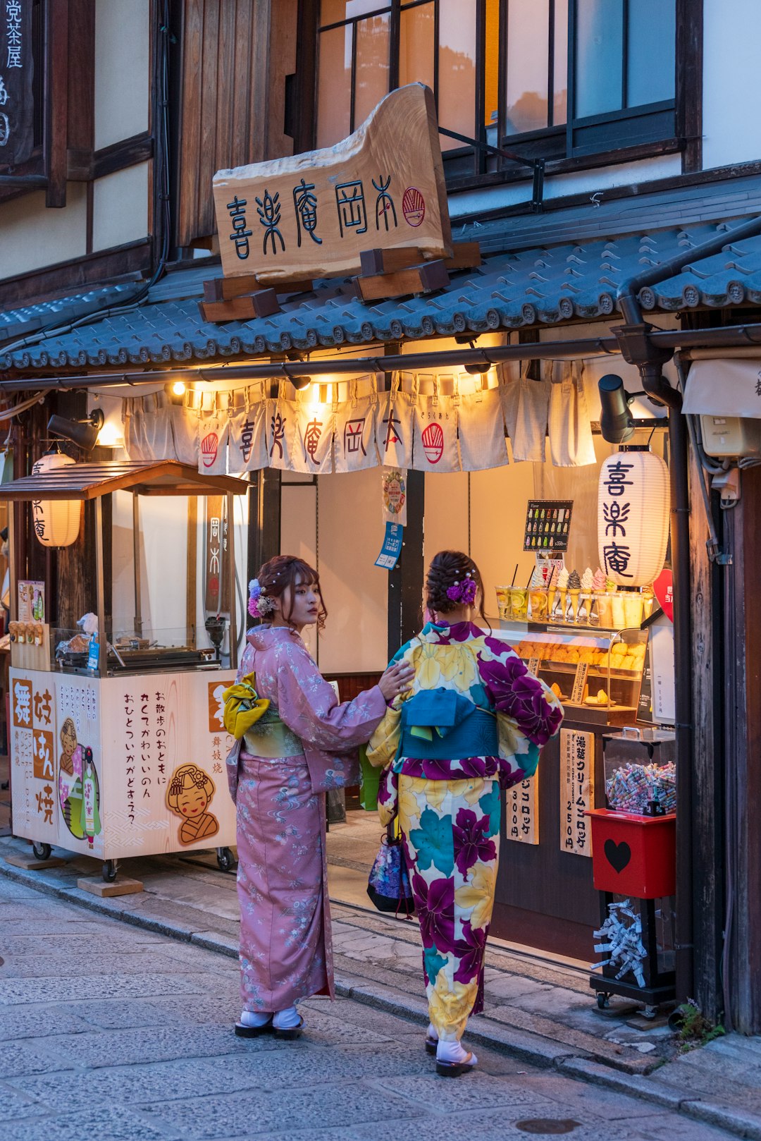 woman in pink green and yellow floral kimono standing beside store