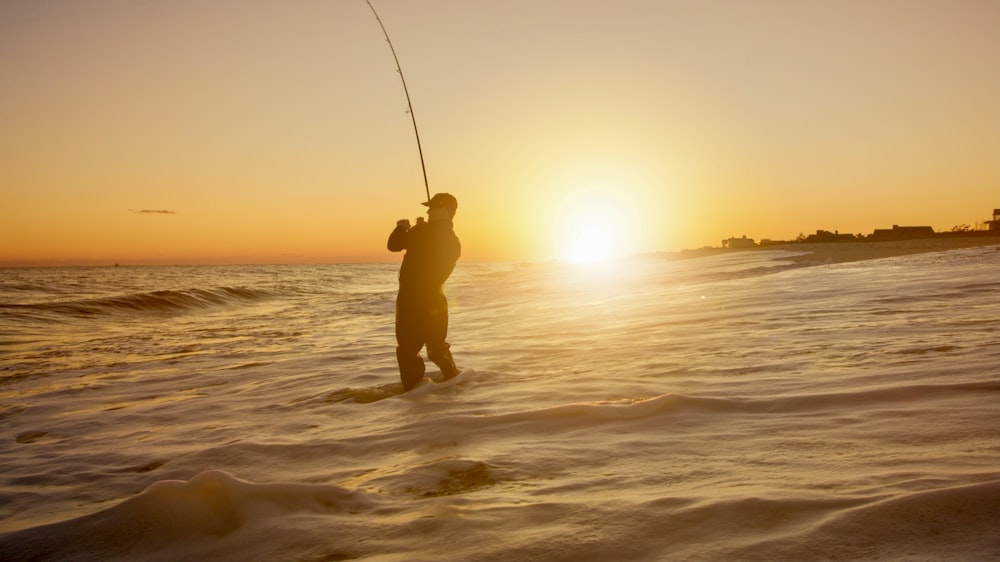 Silhouette eines Menschen, der bei Sonnenuntergang auf See fischt