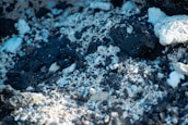 A close-up view of a rocky surface composed of dark, porous stones intermixed with lighter white stones and fine gravel.