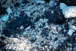 A close-up view of a rocky surface composed of dark, porous stones intermixed with lighter white stones and fine gravel.