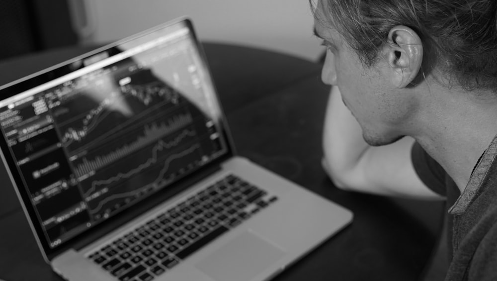 Foto en escala de grises de un hombre mirando el MacBook Pro