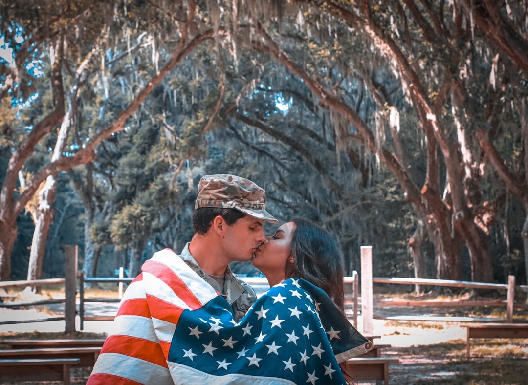 man in blue white and red striped shirt sitting on brown wooden bench during daytime