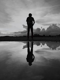 man in black jacket standing on brown wooden dock during daytime