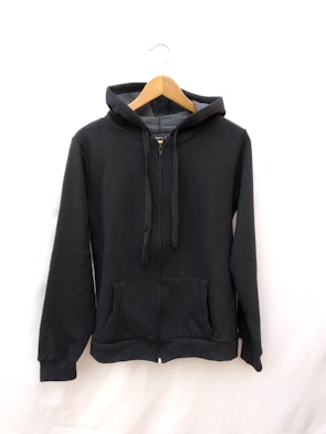 A cozy hoodie displayed on a wooden hanger against a neutral background.