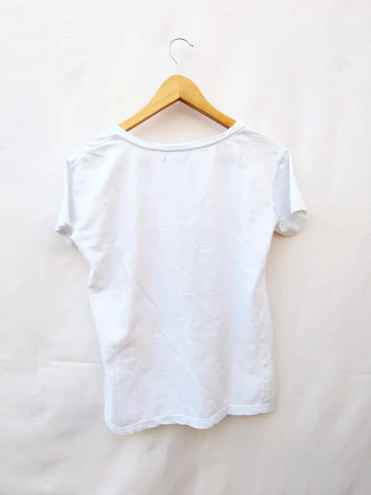 Close-up of a plain white t-shirt with a round neckline displayed on a wooden hanger.