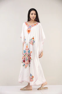 Close-up of a model wearing a flowing, colorful summer dress with delicate embroidery.