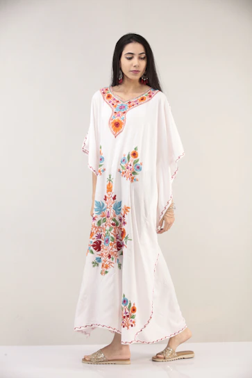 Close-up of a model wearing a flowing, colorful summer dress with delicate embroidery.