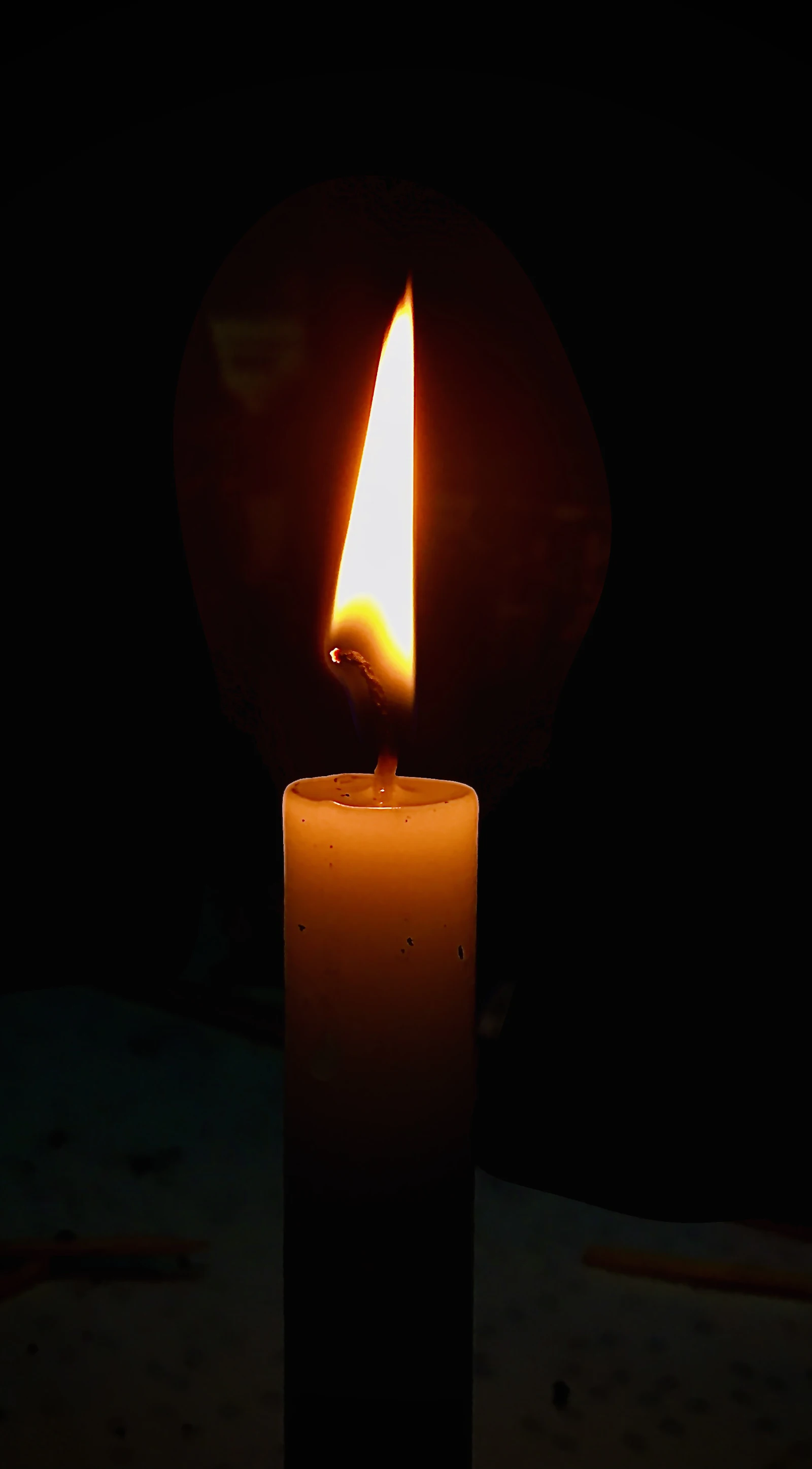 A single candle burning in a dark room