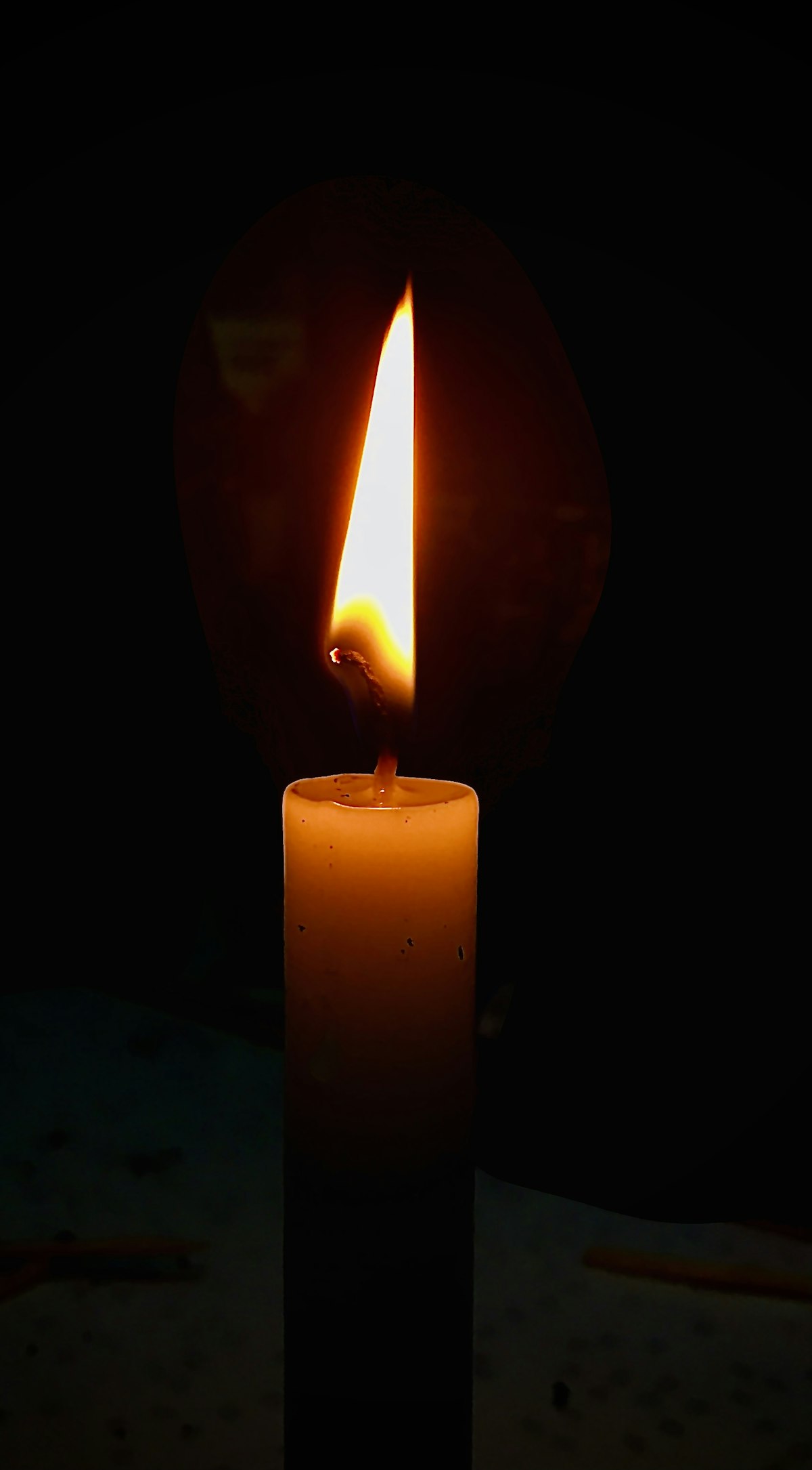 A single candle glowing in the dark, evoking the heavy mood the word sinbyeong carries / 어둠 속 촛불 하나