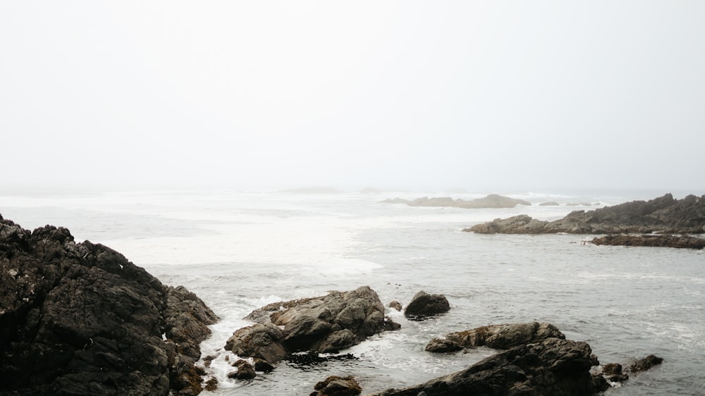 gray rocky shore with ocean waves crashing on shore during daytime