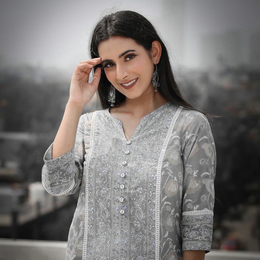 woman in gray and white floral long sleeve shirt holding red sunglasses