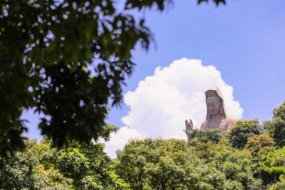 gray concrete statue near green trees under blue sky during daytime