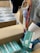 A person wearing gloves, a cap, and a face mask is packing boxes containing surgical masks. The individual is handling a box of 'BYD CARE' labeled surgical masks, placing them into a larger cardboard box.