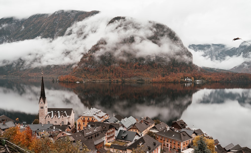 brown and white houses near lake and mountain