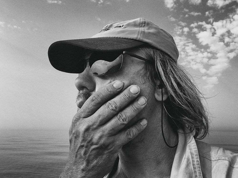 grayscale photo of woman covering her face with her hand