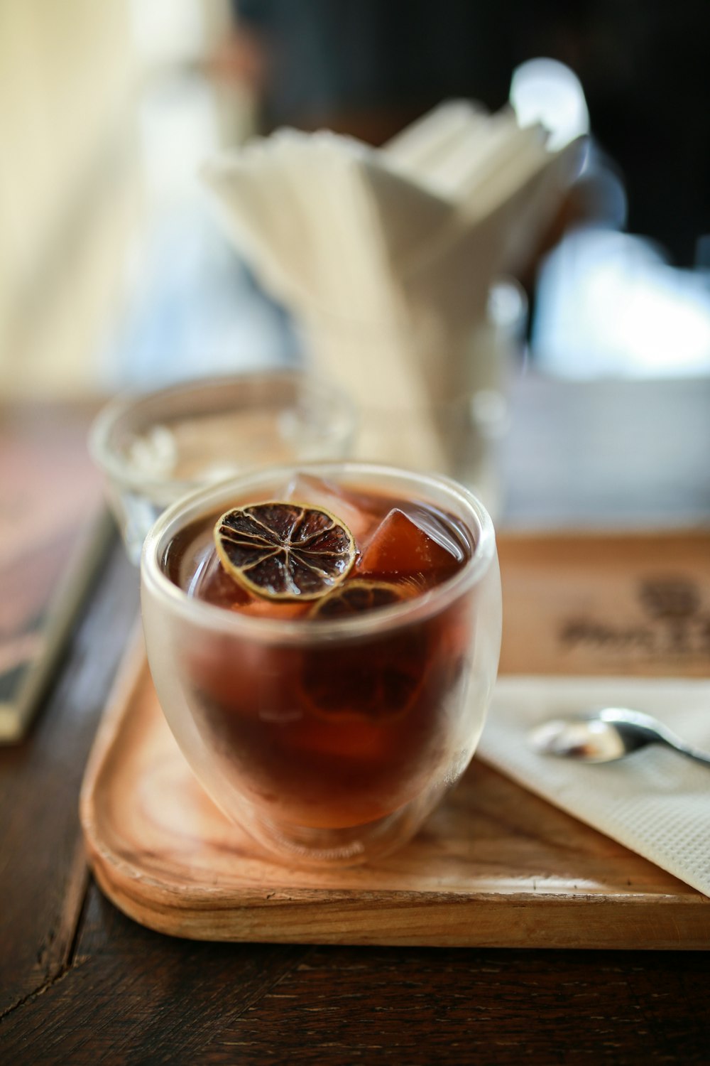 clear drinking glass with brown liquid on brown wooden table